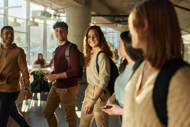 istock Happy college students talking on the move in a school hallway. 2205658321