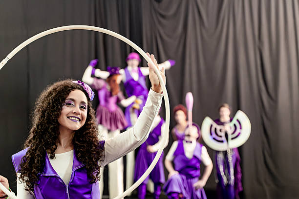 istock Young circus artist performing with hula hoop on stage with acrobats 2205658974