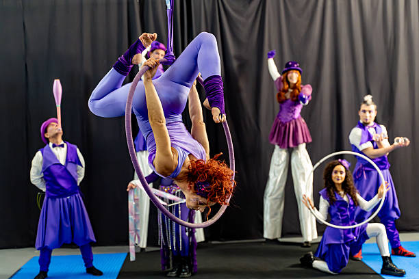 istock Circus performers wearing purple costumes performing acrobatics with hoops 2205658975