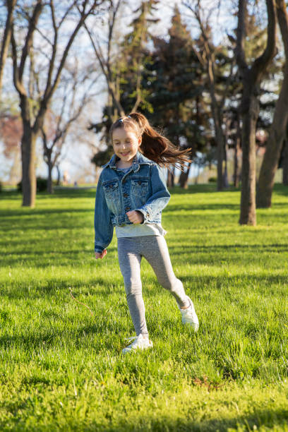 istock Smiling girl running on grass in a park during a sunny day 2205663519