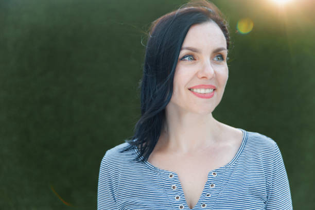 istock Smiling woman looking away from camera with green background 2205663592