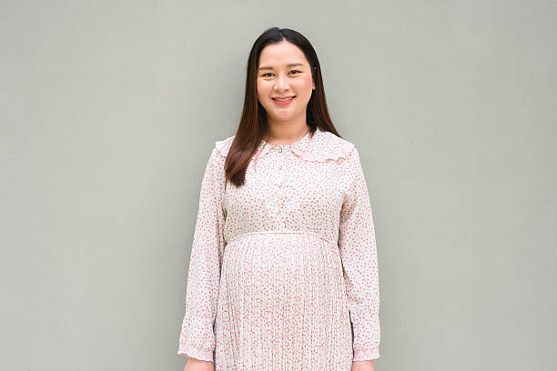 istock Pregnant woman portrait against plain wall 2205663857