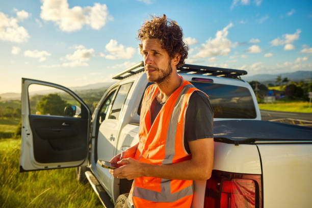 istock Engineer using smartphone leaning on pickup truck in rural australia 2205665829