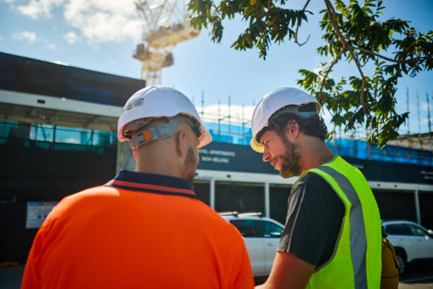 Engineers discussing building plans at construction site in australia