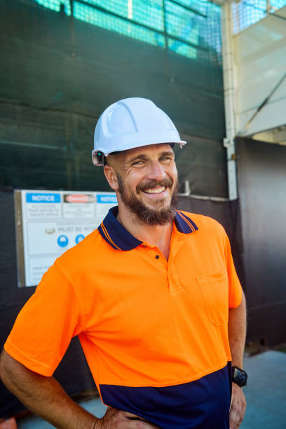 Smiling engineer wearing hardhat at construction site in australia