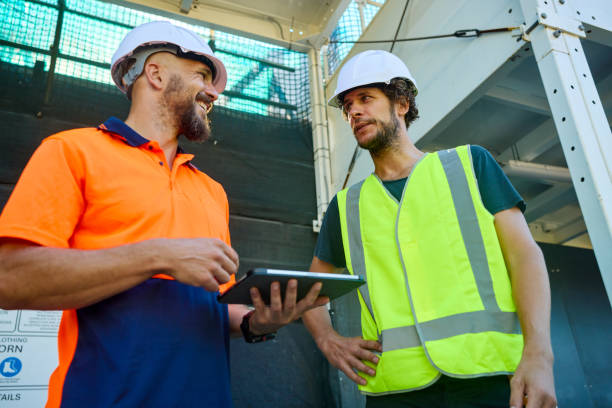 istock Engineers discussing building plans on digital tablet at construction site in australia 2205665871