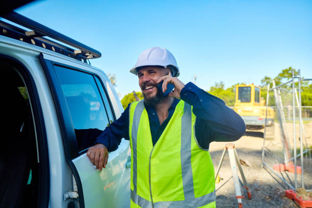 Smiling engineer talking on mobile phone at construction site in australia