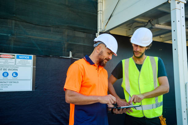 istock Engineers discussing building plans on digital tablet at construction site in australia 2205665900
