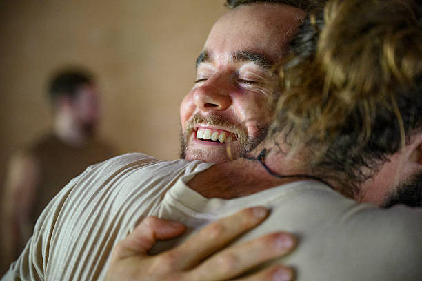 Mid adult man with eyes closed and cheerful expression hugging male friend, affection, bonding, male bonding