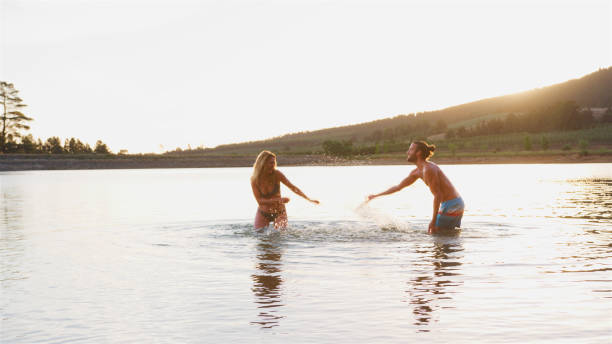 istock Romantic Couple Splashing In Lake Backlit By Evening Sun 2205668433