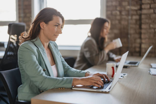 Focused Woman Typing at Laptop in an Office Setting