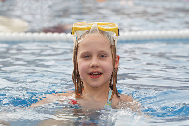Portrait of a happy girl whit swimming googles in swimming pool