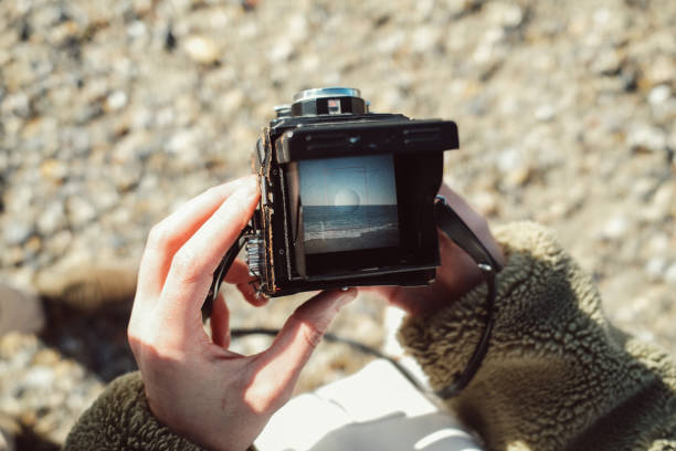 Photo of a mid adult man, capturing some photos of the beach at wintertime with his vintage camera Yasicha