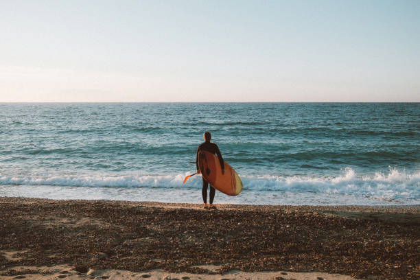 istock Male surfer holding a surfboard at the beach 2205673949
