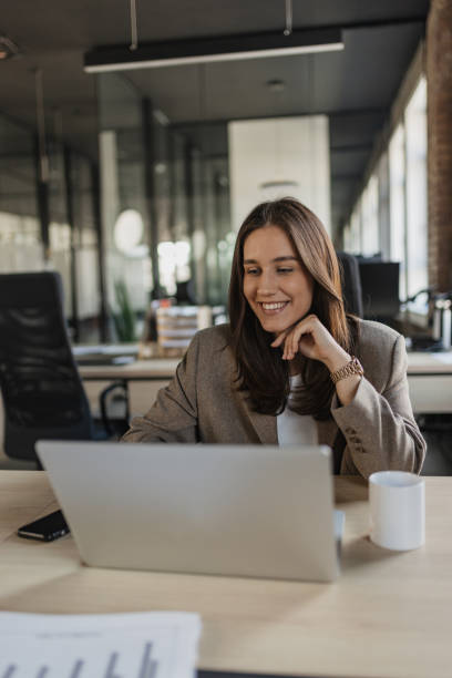 istock Smiling Woman Pondering Over Laptop in Office 2205674672