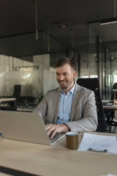 istock Smiling man working on laptop in modern office 2205674726