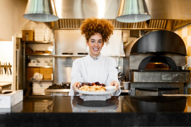 istock Female Chef Proudly Presenting a Dish in a Restaurant Kitchen 2205674989