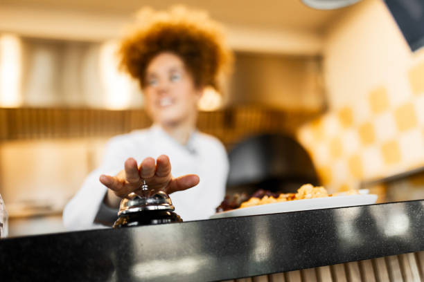 Female Cook Ringing Service Bell While Serving a Fresh Dish