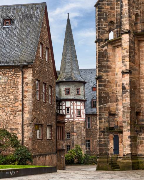 A picturesque view of historic European architecture featuring stone buildings and a spire under a blue sky.