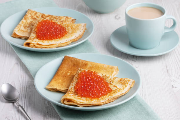 istock Savory crepes filled with fresh orange fish roe served on a light blue plate at a cozy breakfast table 2205675503