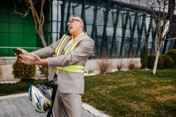 Businessman wearing suit while going to work with electric push scooter and stopped for important phone call on his mobile phone