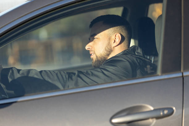 istock A handsome man sits focused behind the wheel, driving a car 2205676666