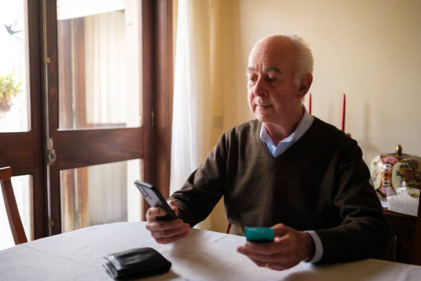 istock Senior man making online payment using smartphone and credit card at home 2205677437