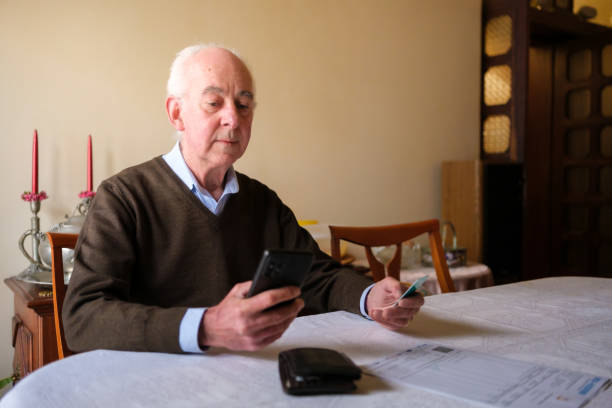 istock Senior man making online payment using smartphone and credit card at home 2205677451