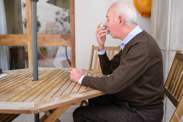 istock Senior man using inhaler for asthma or respiratory problems at home 2205677551