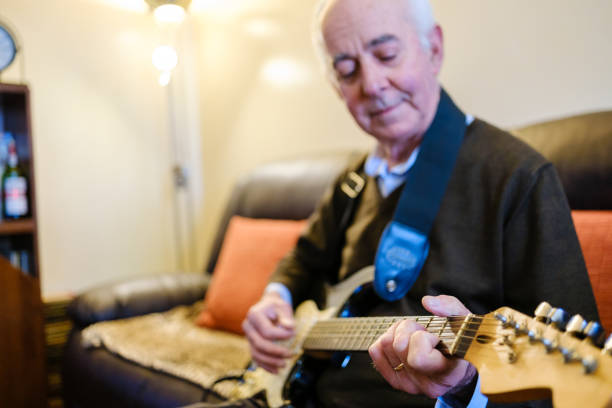 istock Senior man playing electric guitar at home on the sofa 2205677862