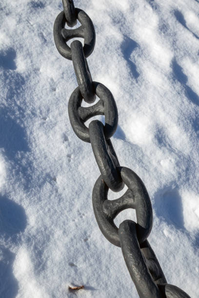 istock thick black chain against white snow in winter 2205678417