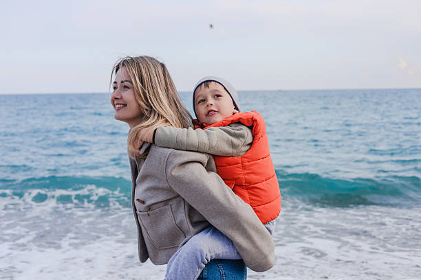 istock Mother plays with son on a winter beach day while collecting pebbles 2205681101