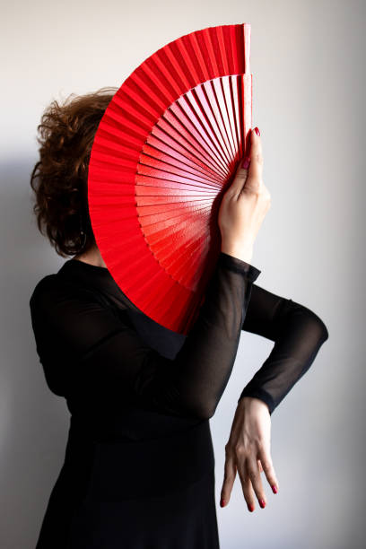 istock Female dancer with red fan in elegant black attire 2205686086