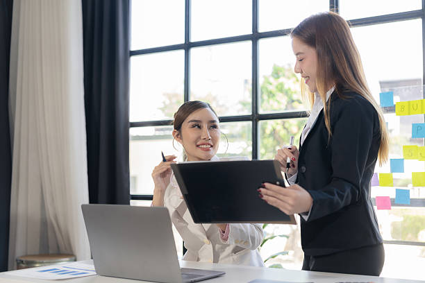 istock Two Asian women talk, consult, discuss work with presentation of new project idea, analyze business marketing plan. 2205686303