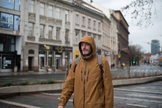 Young man with hood and backpack enjoying walk in city