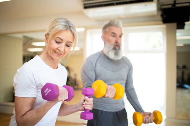 istock Mature woman with her partner exercising with dumbbells 2205687782