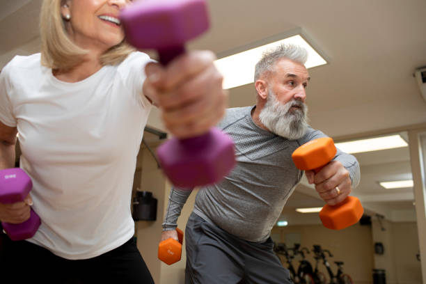 istock Mature couple exercising in unison with dumbbells 2205687812