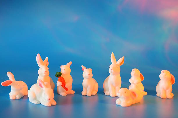 istock Toy white hares on a blue background. Animal figurines. 2205689451