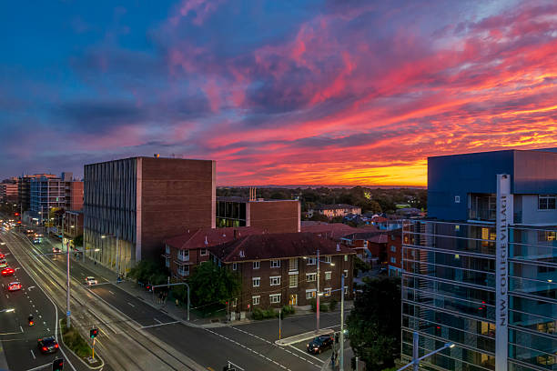 Sydney, Australia - Apr 13, 2016: Dramatic sky with intense sunset colors over suburban buildings. Elevated view. Light vehicle traffic along Anzac Parade in the foreground.