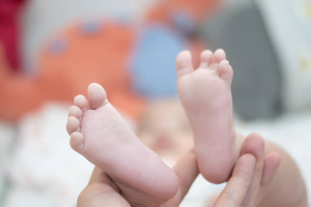 istock Baby's feet are being held up by a person 2205692015