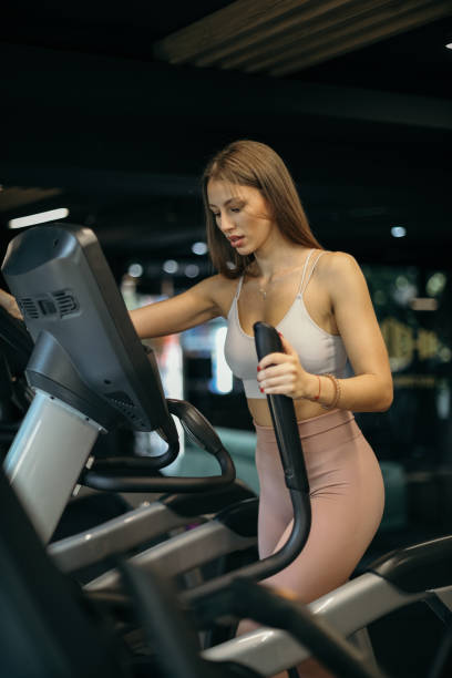istock Woman Exercising on Elliptical Stepper in Gym 2205692661