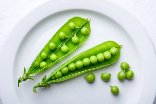 istock Top view on green sugar snap peas on white plate 2205692683