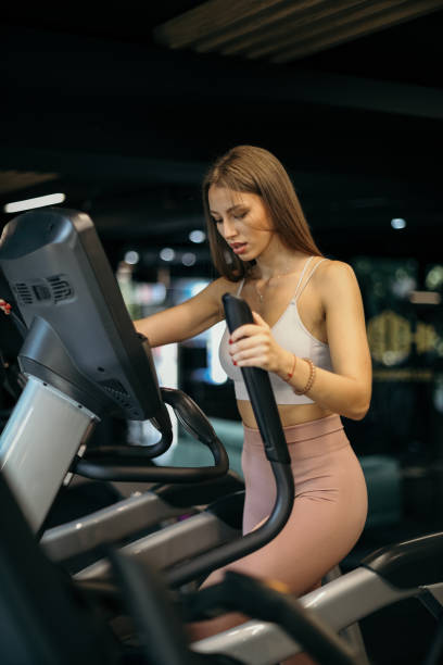 istock Woman Exercising on Elliptical Stepper in Gym 2205692880