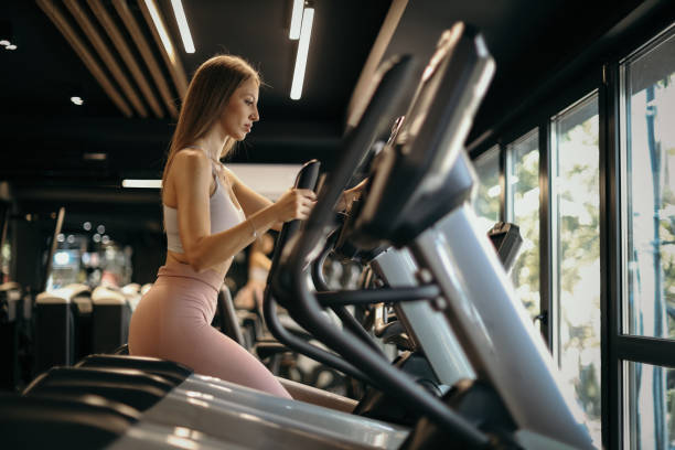 istock Young Woman Using Elliptical Machine in Gym 2205693046