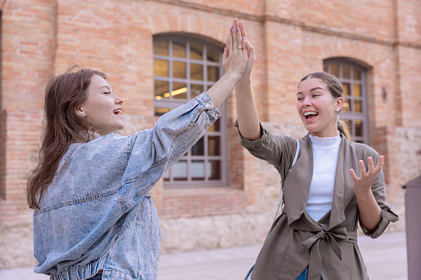 istock Two happy young women giving a high five outdoors in an urban setting 2205693360
