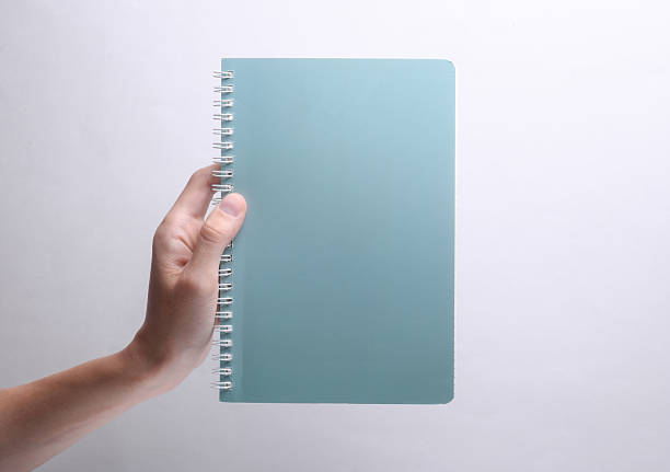 Female hand holding spiral notebook on grey background