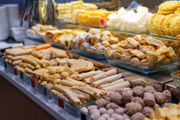 A variety of dried snacks, fish balls, and seafood sticks neatly arranged in a glass display at a local market. The selection includes crispy, puffed, and flavored options. These ingredients are commonly used in Asian cuisine and steamboat dining.