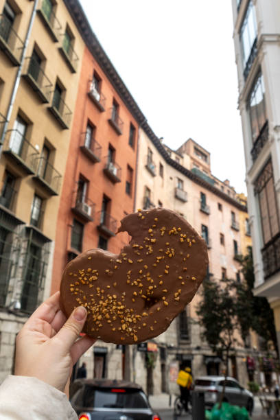 istock A person holds a chocolate heartshaped donut by a building 2205702240