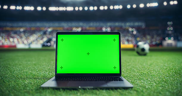 istock Laptop Computer with Green Screen Mock Up Display with a Soccer Ball Rolling in the Background on a Stadium Field at Night. Template for Software, Streaming, Sports Betting, Multimedia Content 2205704947