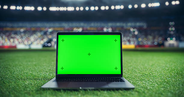 istock Laptop Computer with a Green Screen Mock Up Display on a Soccer Stadium Field at Night. Template for Software, Streaming, Sports Betting, Multimedia Content and Social Media Management 2205704952